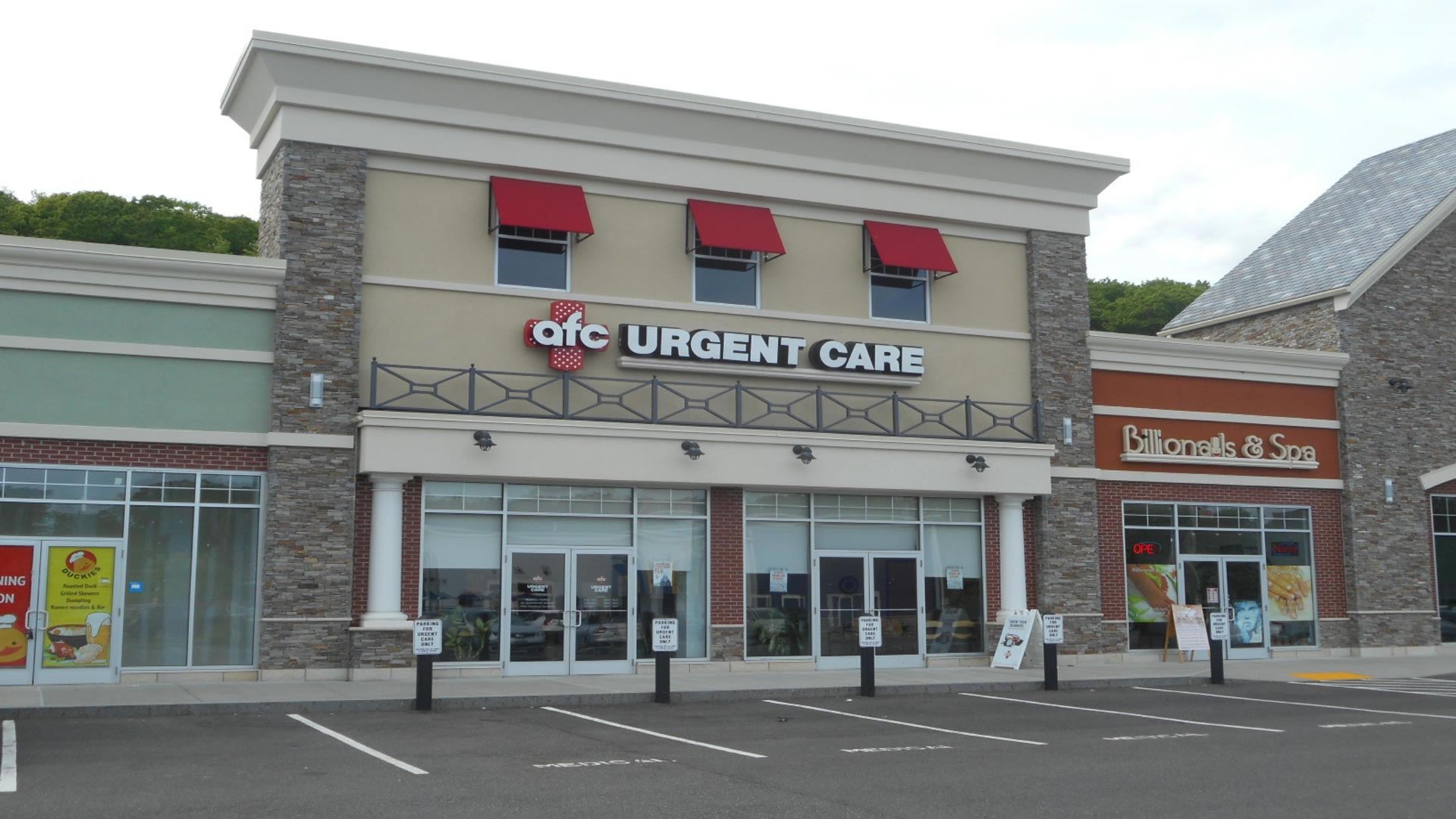 AFC Urgent Care in a strip mall, brick and cream facade, red awnings.