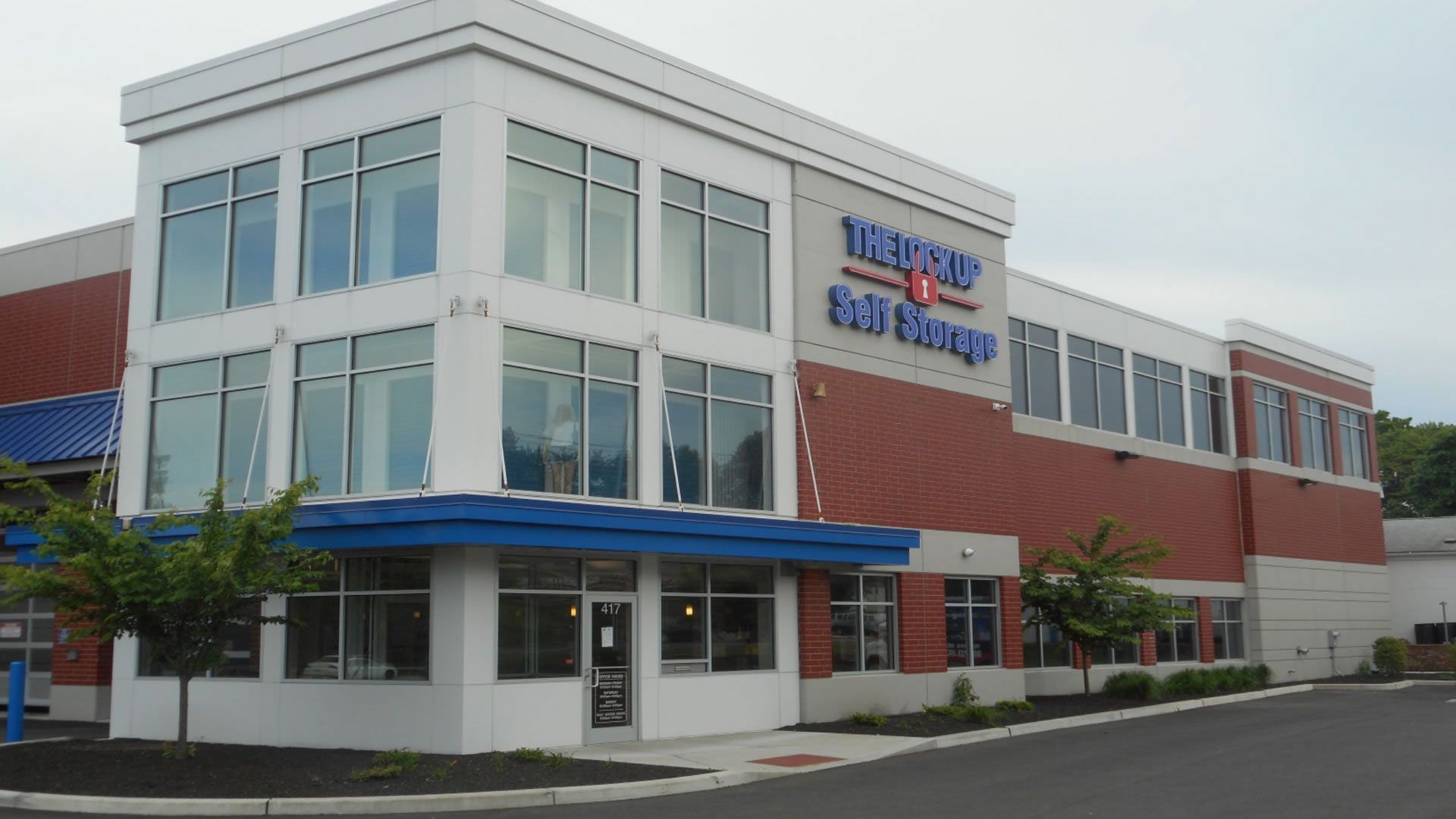 Modern self-storage facility building with large windows and a blue awning; brick and white exterior.