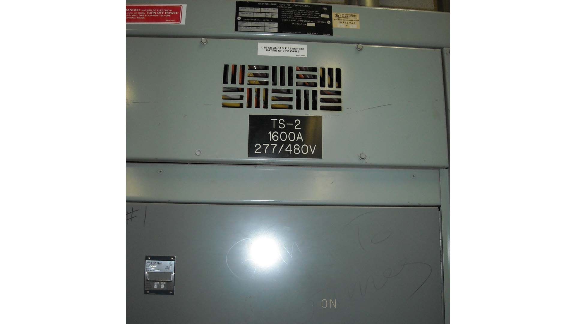 Gray electrical panel with labels and ventilation slots.