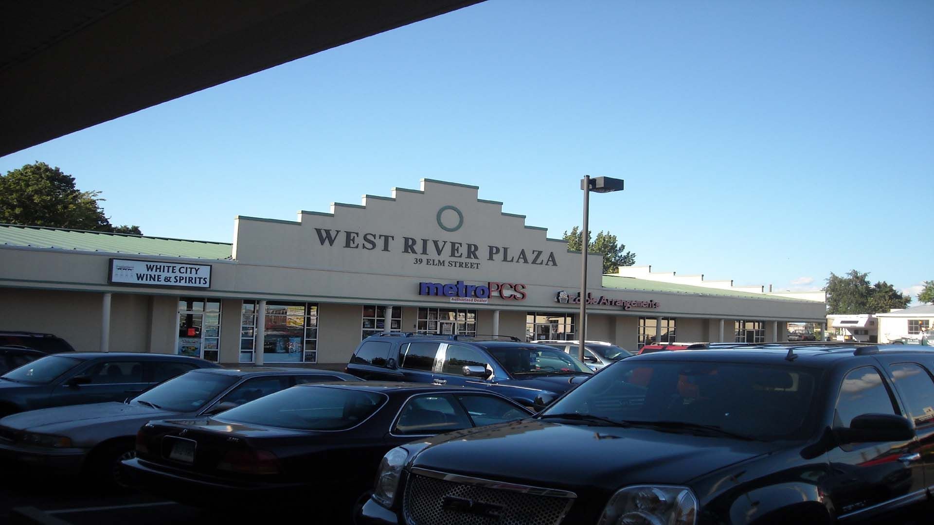 West River Plaza exterior; cars parked in front of a strip mall with a blue sky.