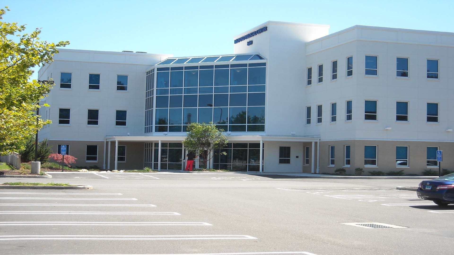 Office building with large glass windows and a parking lot.