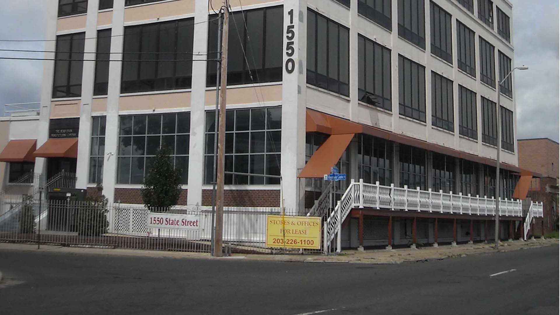 Building at 1550 with awnings, large windows, and stairs leading to the entrance on a street corner.