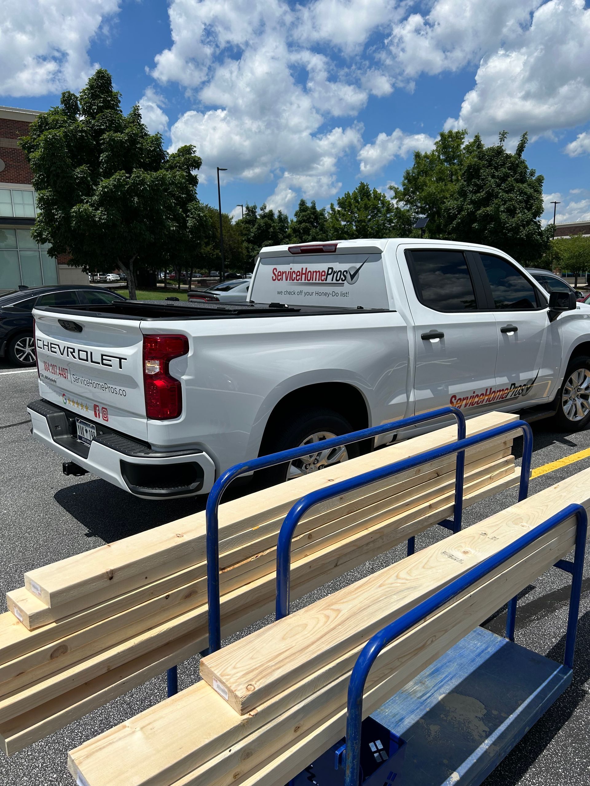 A white truck is parked next to a stack of wood.