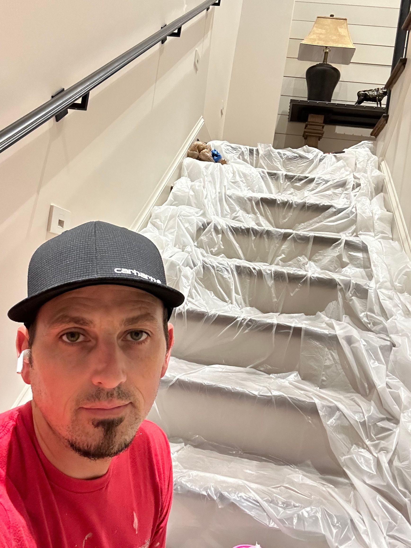 A man is taking a selfie in front of a set of stairs covered in plastic.