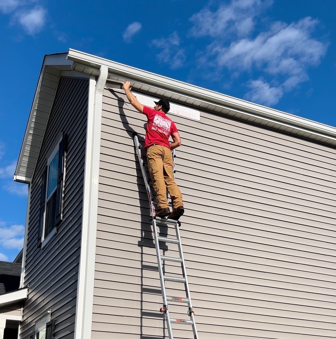 A man is standing on a ladder on the side of a house.