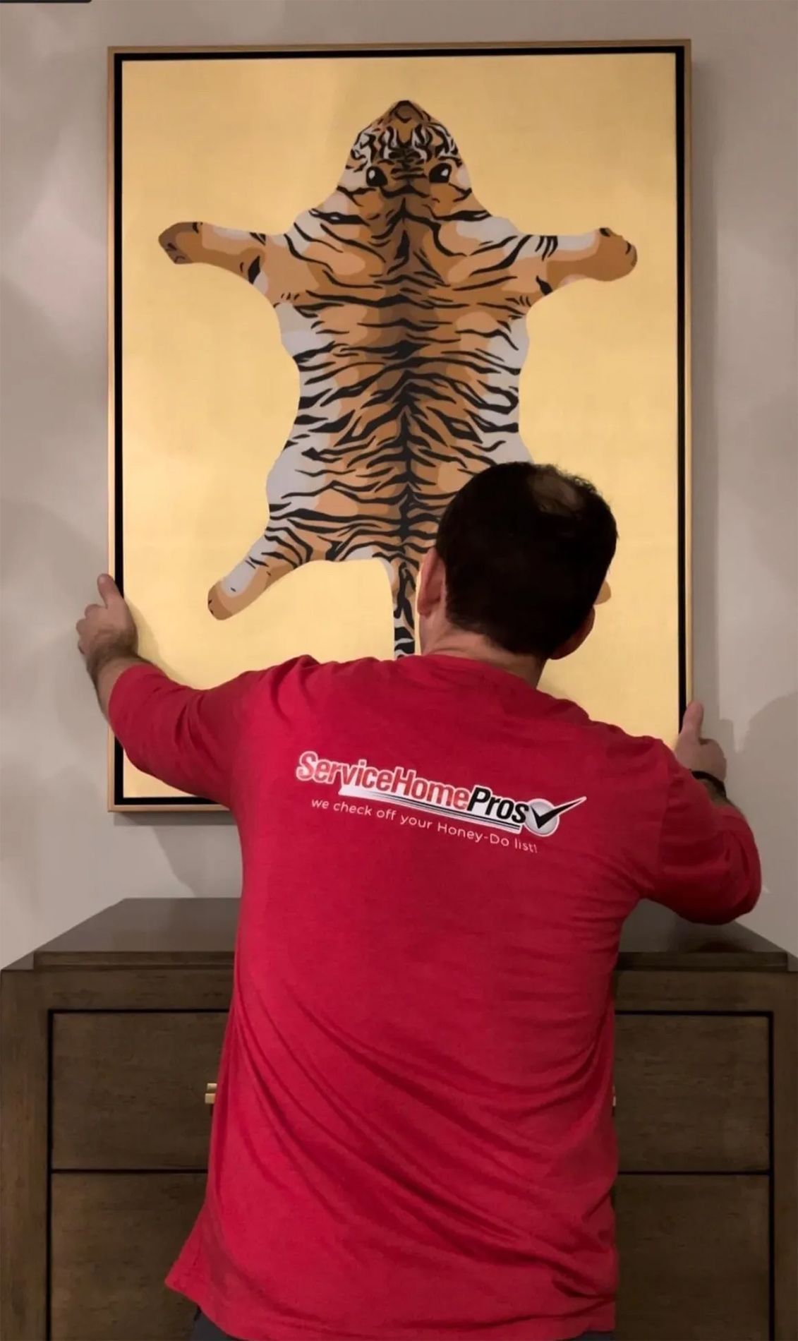 A man in a red shirt is holding up a picture of a tiger