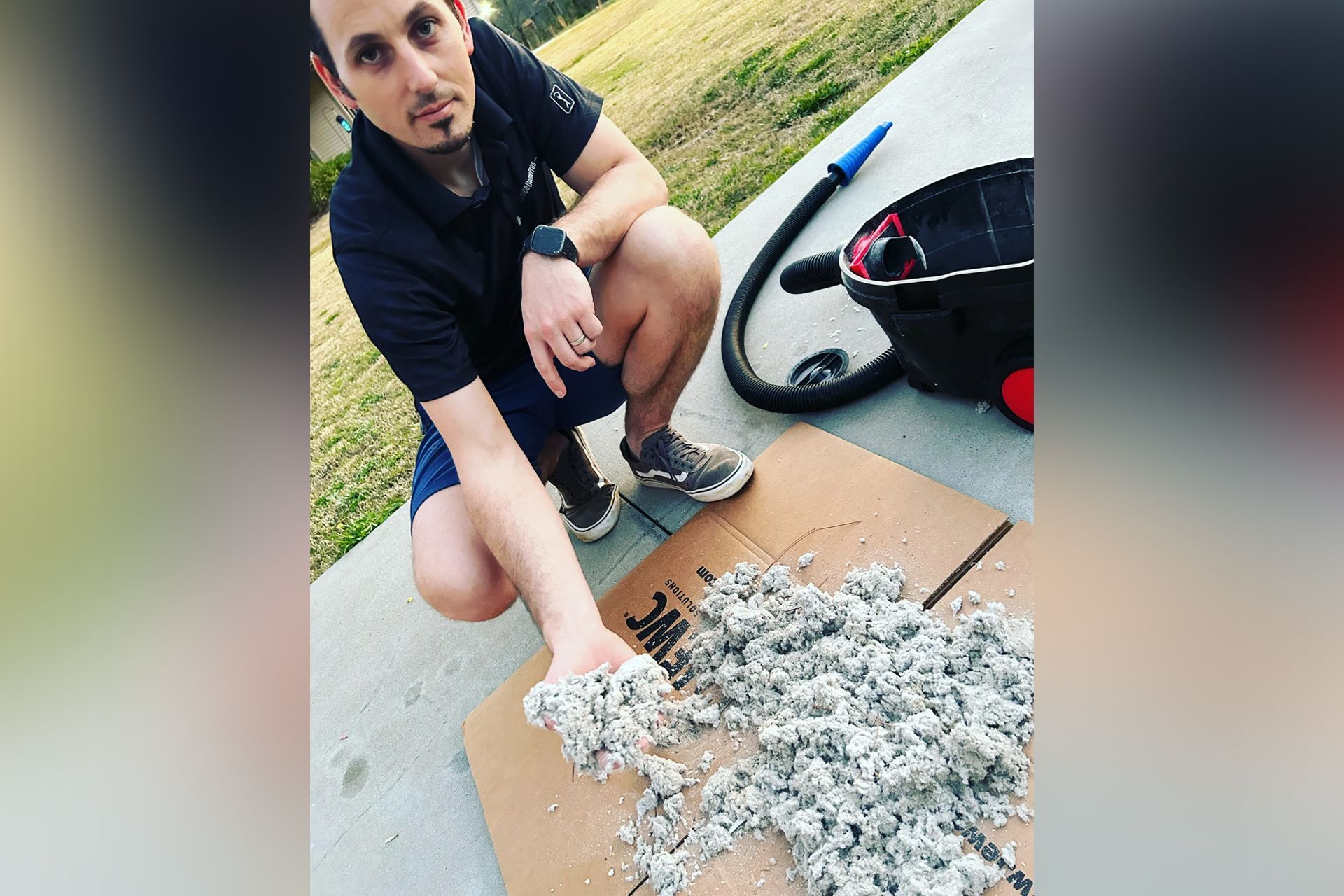 A man is kneeling on a cardboard box holding a pile of cotton.