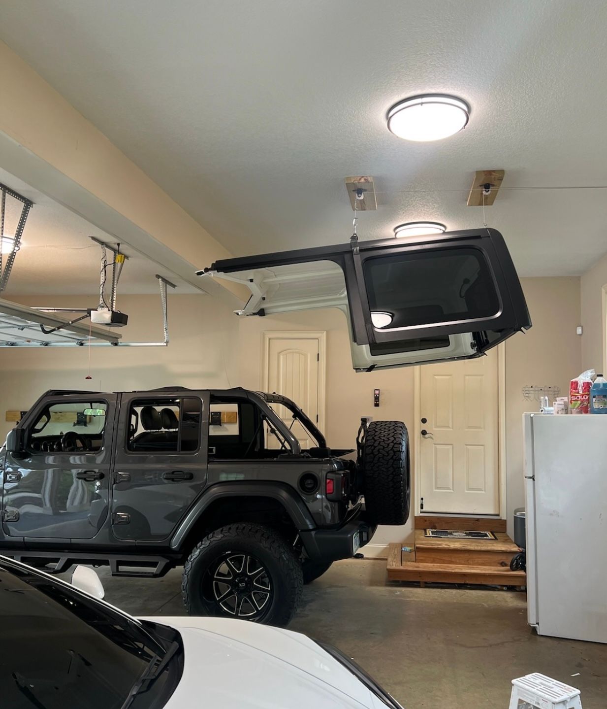 A jeep is parked in a garage with its trunk open.