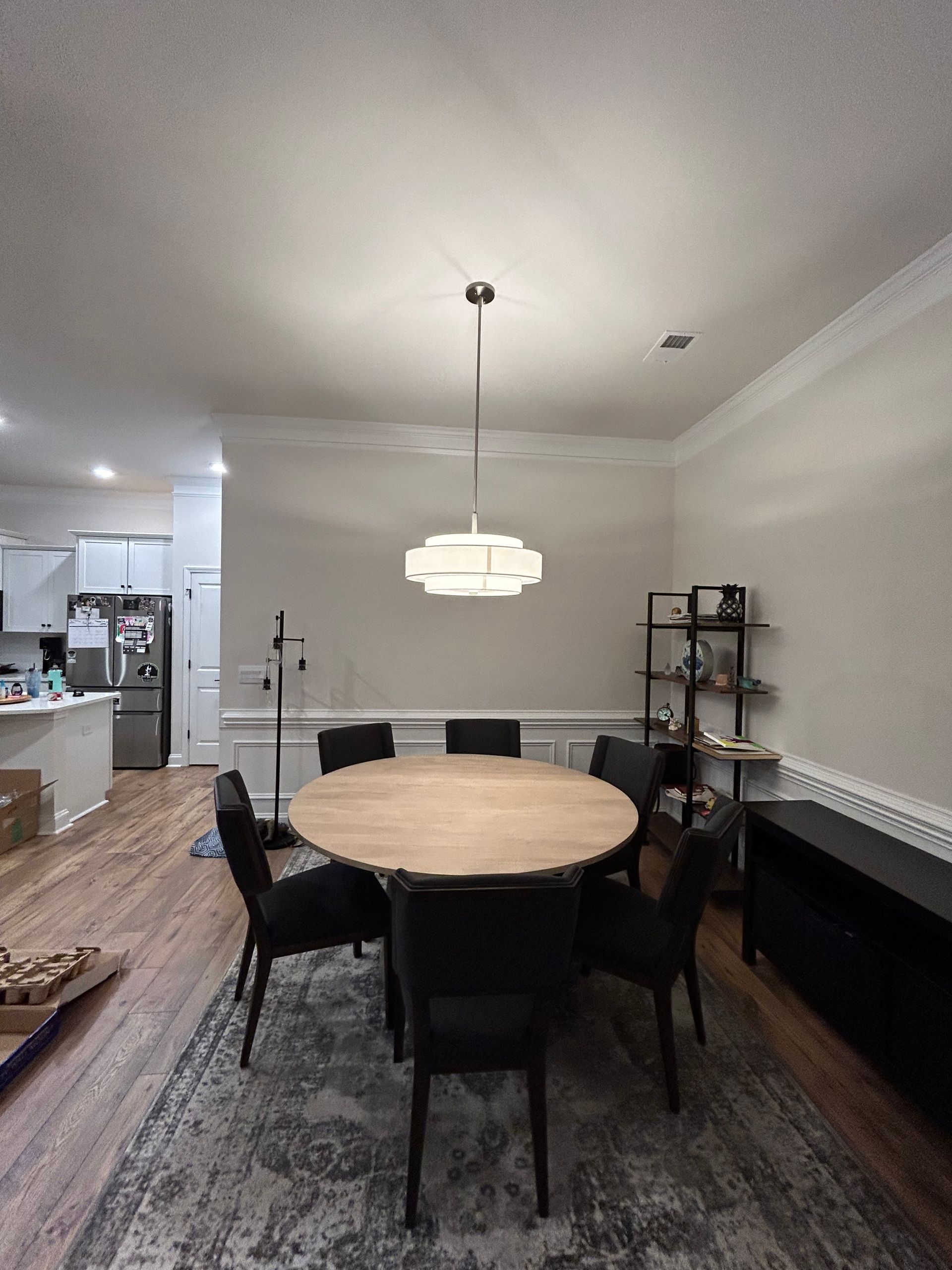 A dining room with a round table and chairs and a chandelier hanging from the ceiling.