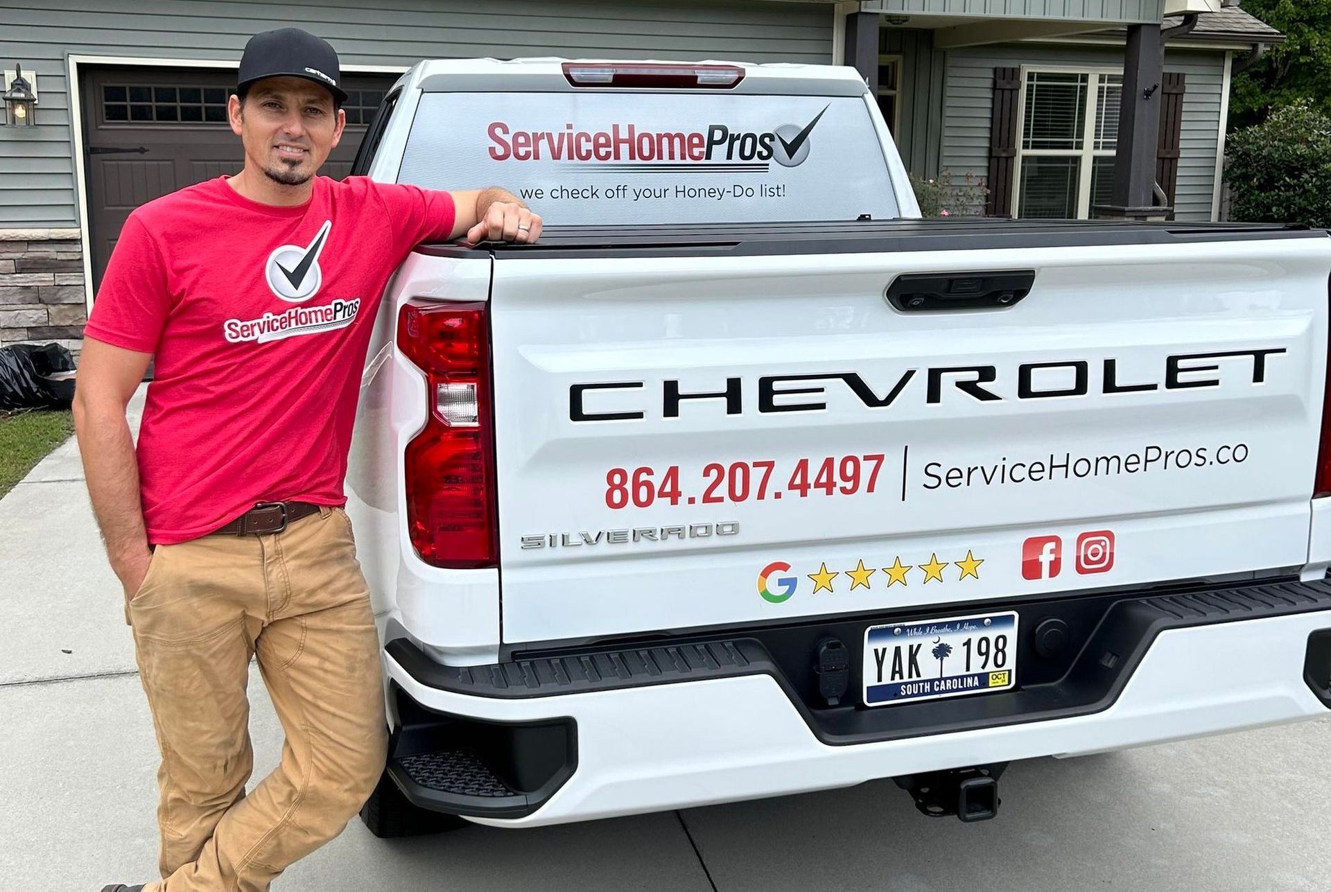 A man in a red shirt is standing next to a chevrolet truck.