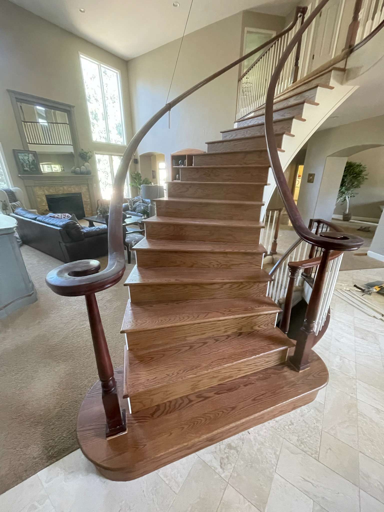 A wooden staircase with a curved railing in a living room.