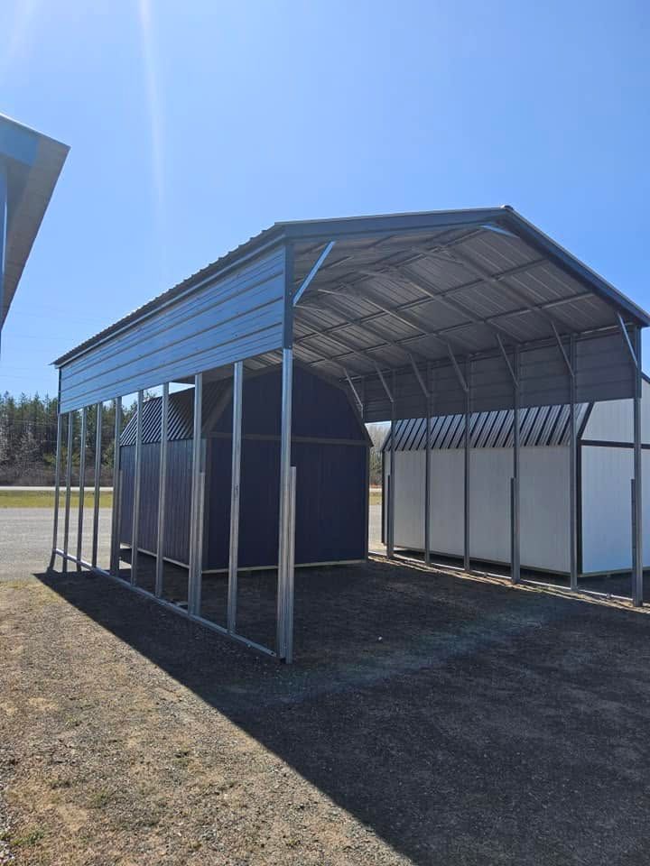 Open-sided metal carport with a gravel floor and blue sky overhead