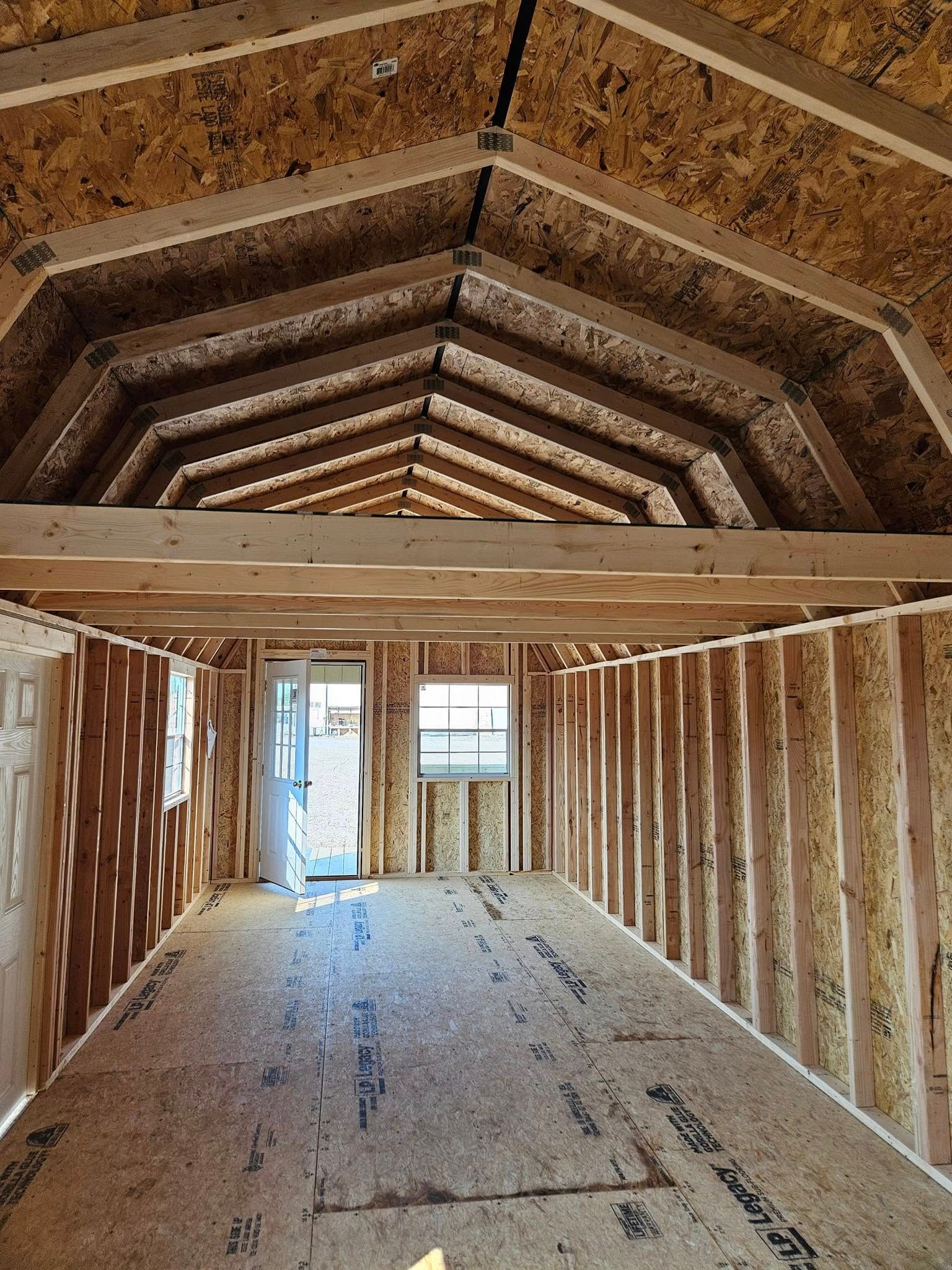 Interior of a wooden shed under construction with exposed roof trusses and unfinished walls.