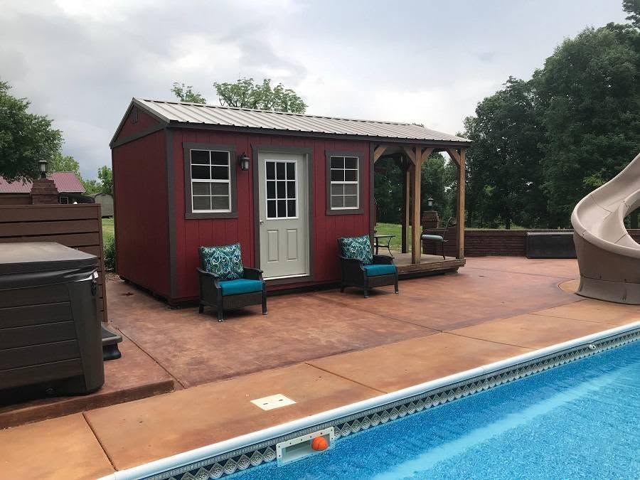 Backyard pool with a small red cabana, patio seating, and a slide in the background