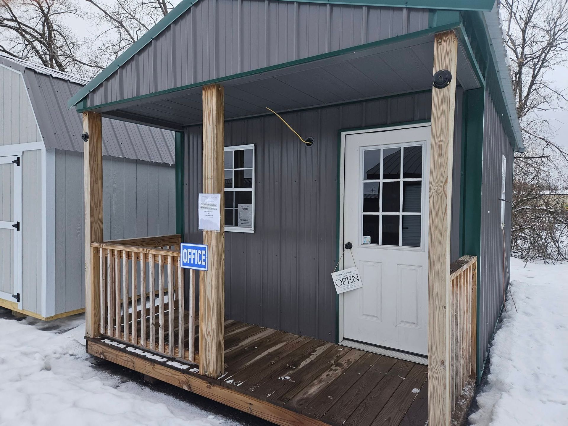 Small gray cabin with porch and white door in a snowy yard