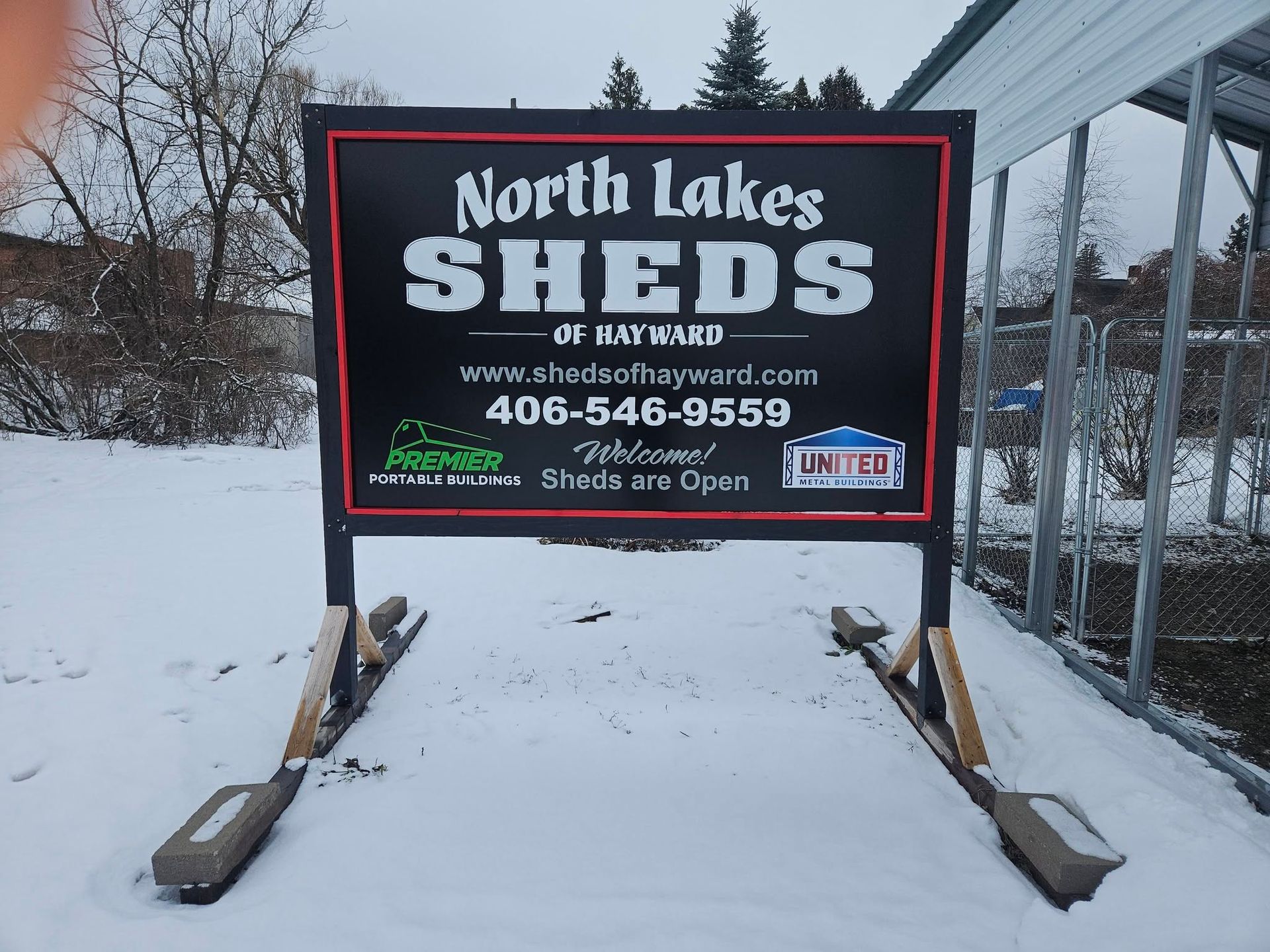 Snowy roadside sign for North Lakes Shell, advertising free air and car wash with phone number.