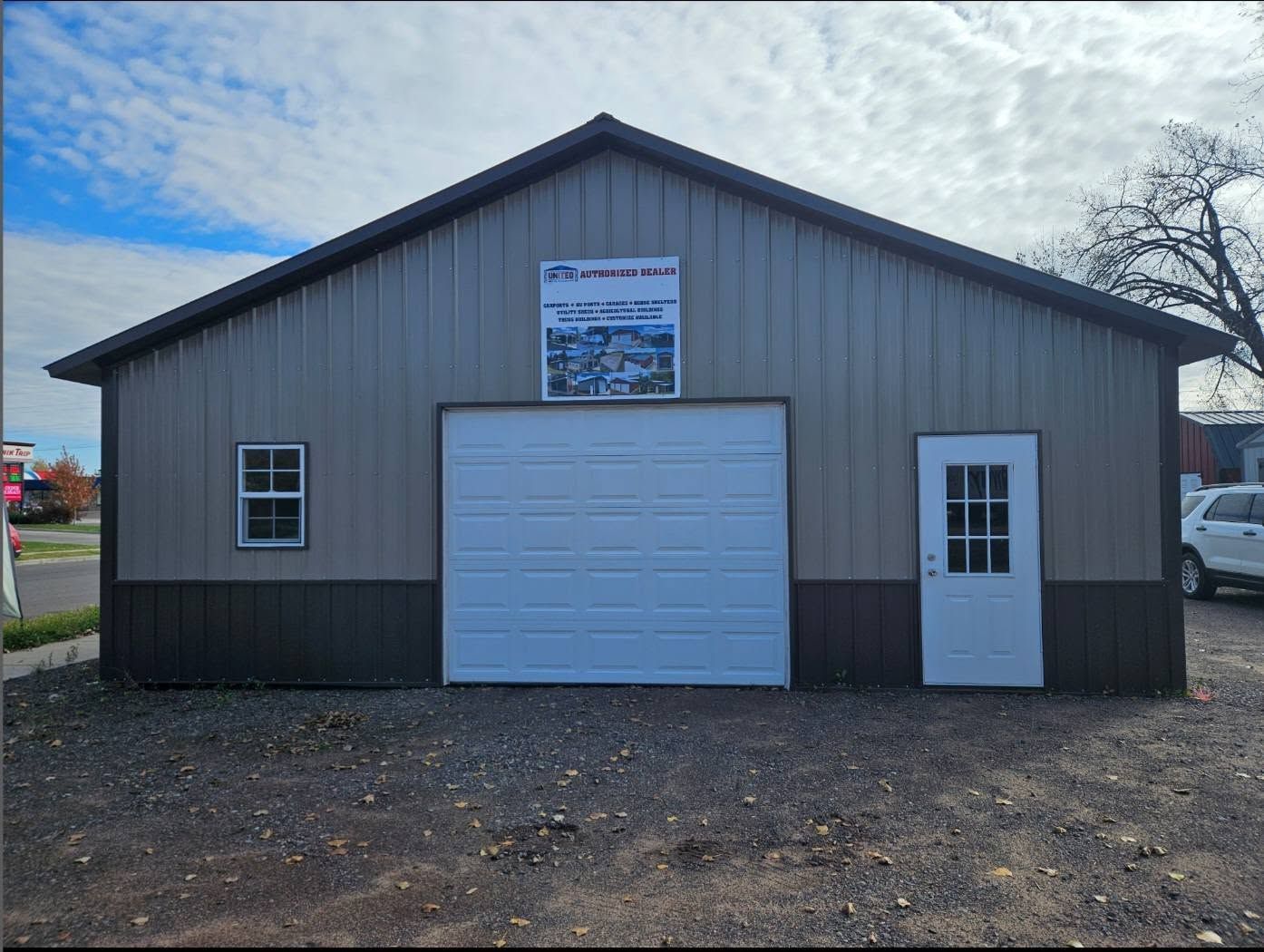 Gray metal building with a large garage door and side entry door under a blue sky