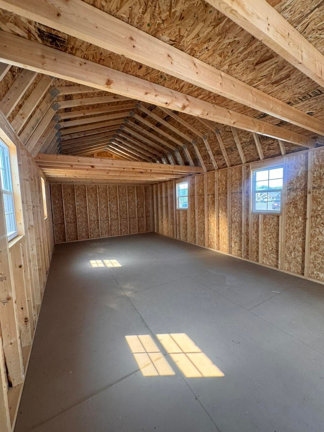 Empty unfinished attic room with exposed wooden framing and sunlight on the floor
