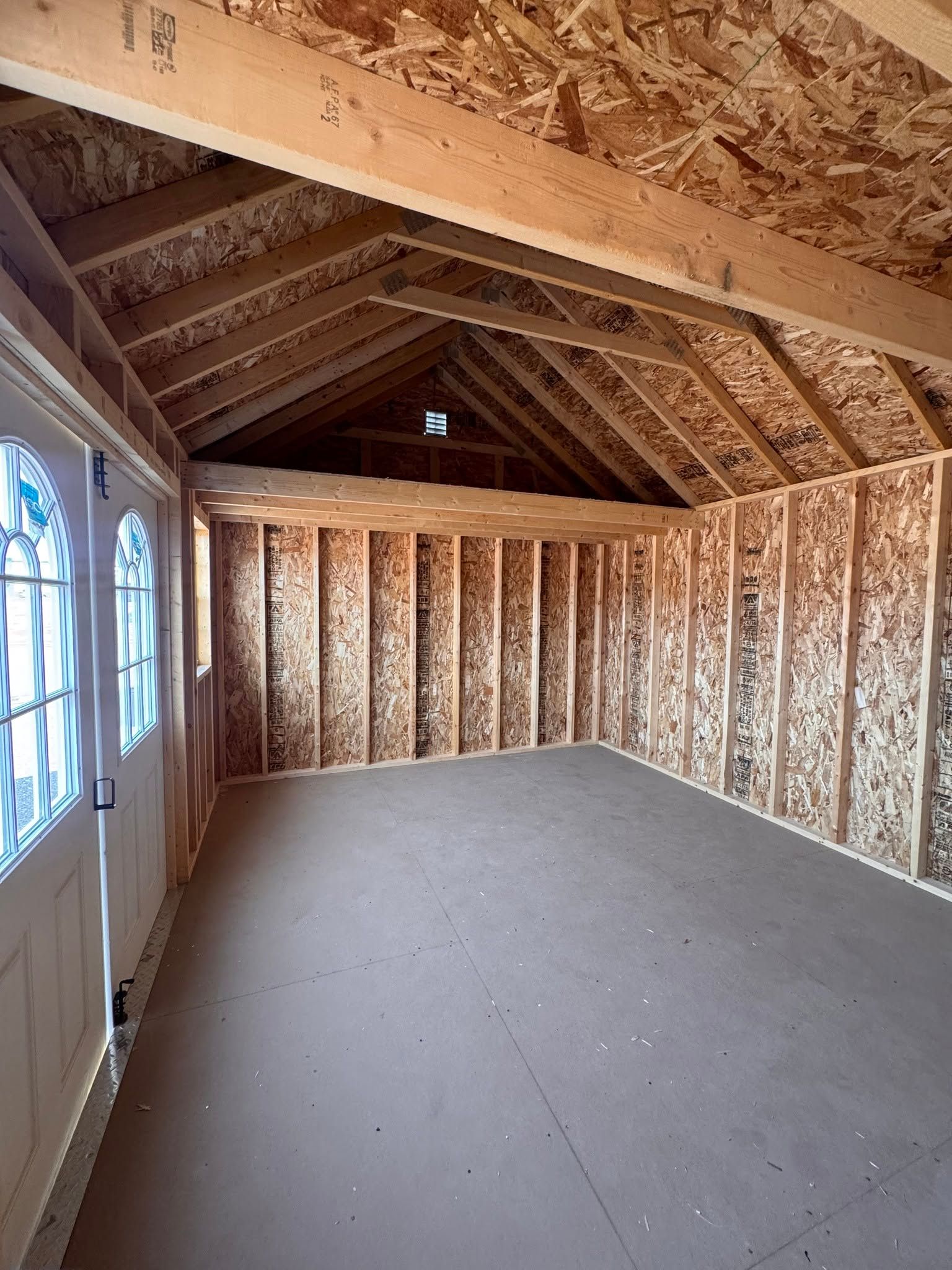 Unfinished attic with exposed wooden framing, pitched roof, and a window on the left.