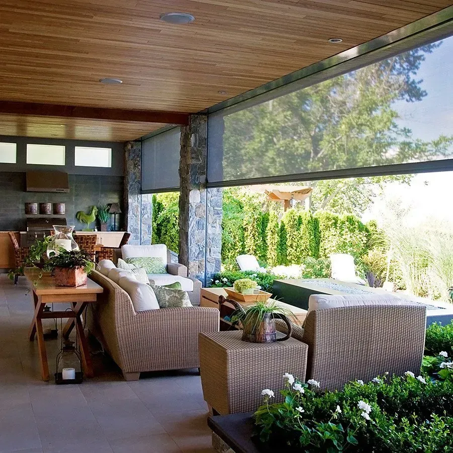 Outdoor patio with wicker furniture, partially screened in, with a view of greenery.