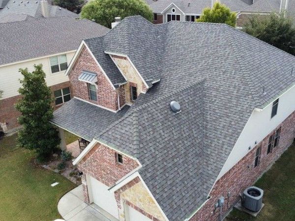 An aerial view of a large brick house with a gray roof.