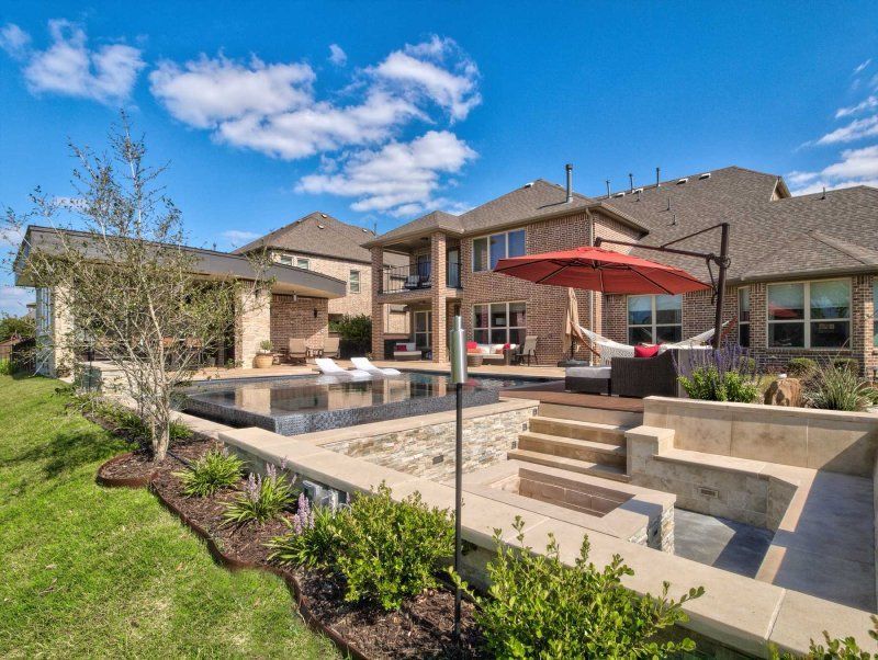 A large house with a swimming pool and an umbrella in front of it.