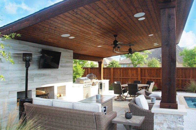 A patio with a couch , chairs , tables , and a fireplace.
