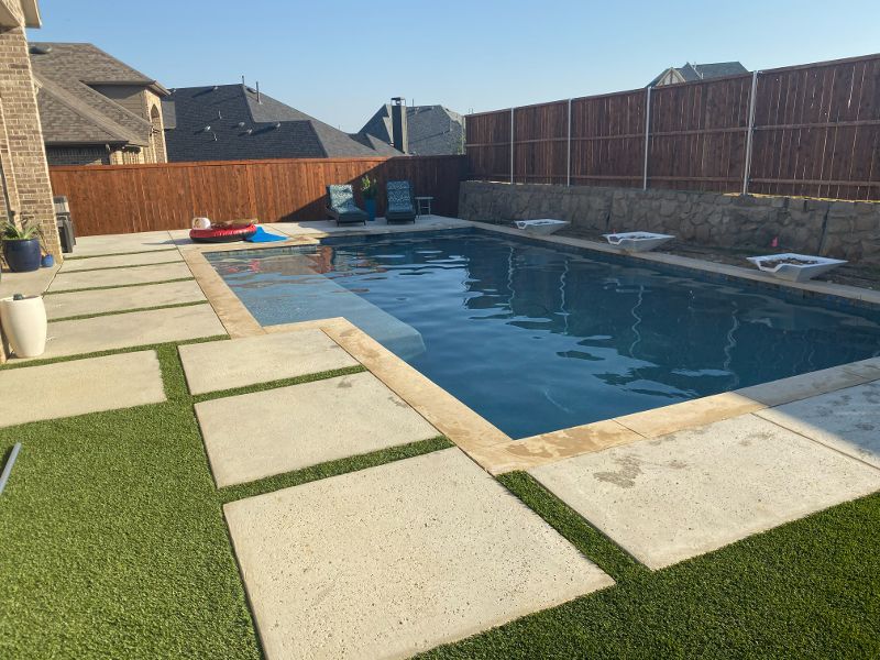 A large swimming pool in a backyard with a wooden fence surrounding it.
