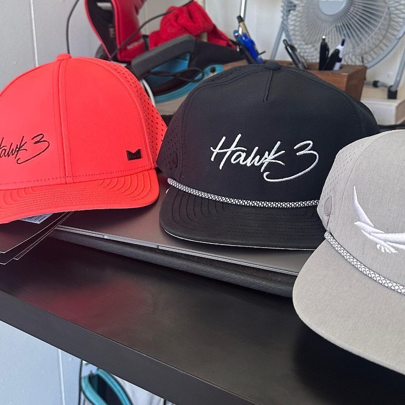 Three hats on a shelf one of which says hawk 3