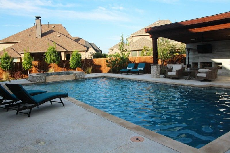 A large swimming pool surrounded by chairs and a pergola
