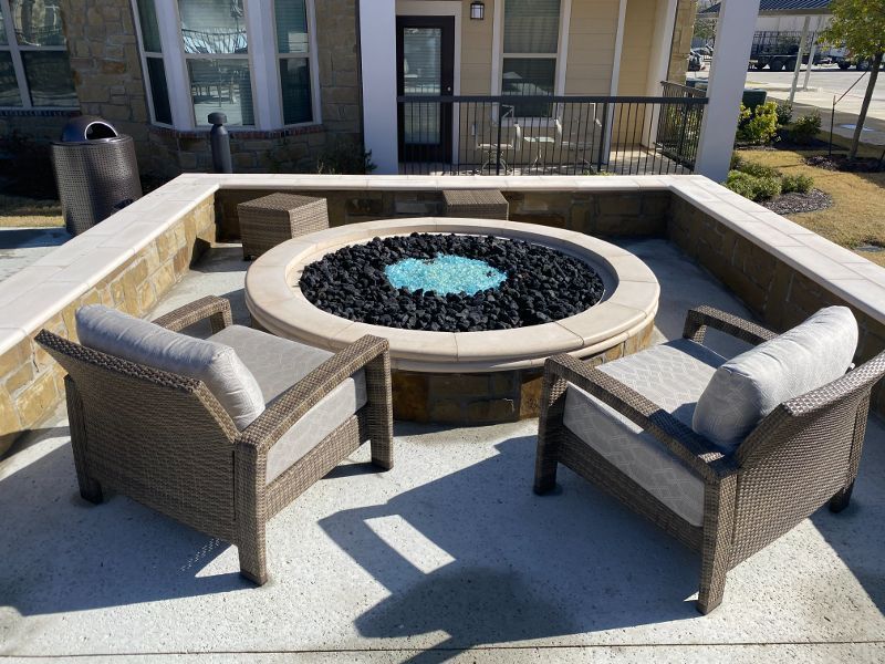 A fire pit is surrounded by chairs on a patio