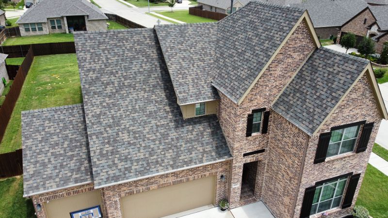 An aerial view of a large brick house with a gray roof.