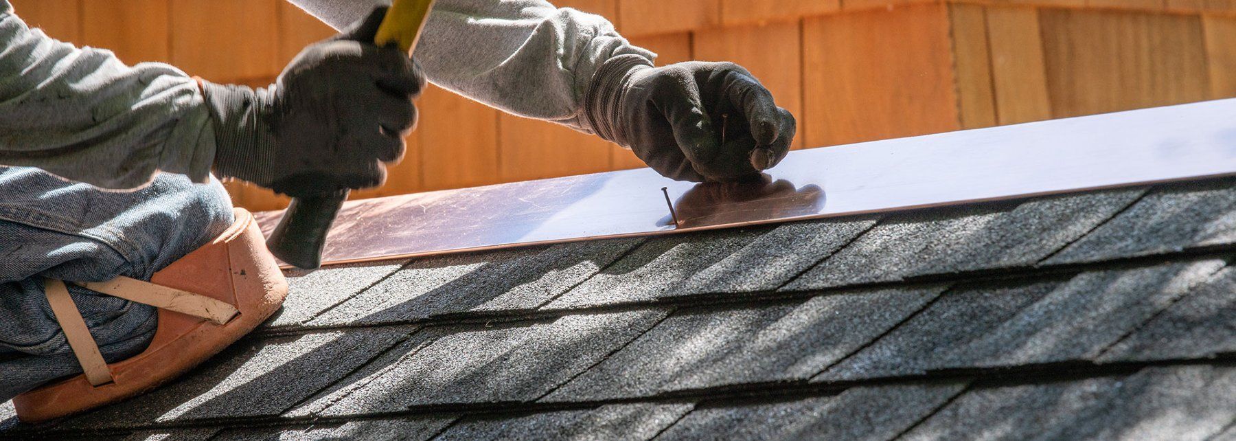 A man is working on a roof with a hammer and pliers.