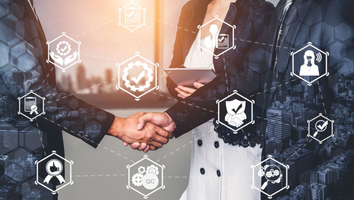 People in business suits shake hands; digital icons overlay.