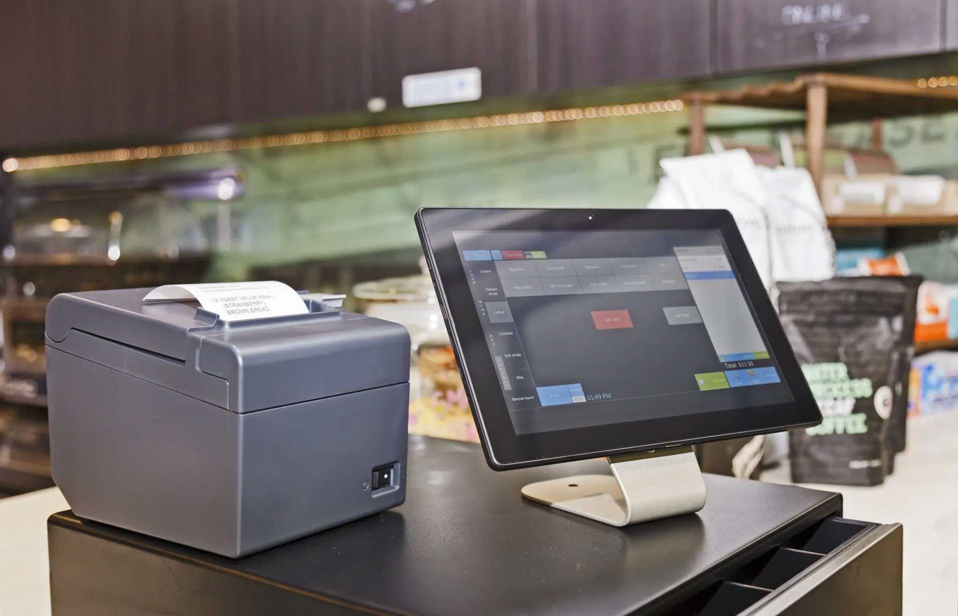 Cash register with tablet screen and receipt printer on a counter in a cafe.