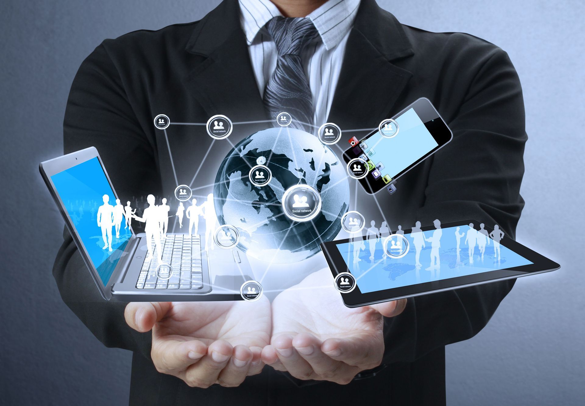 A person in a suit holds a digital globe surrounded by icons, a laptop, and a tablet, representing global connectivity.