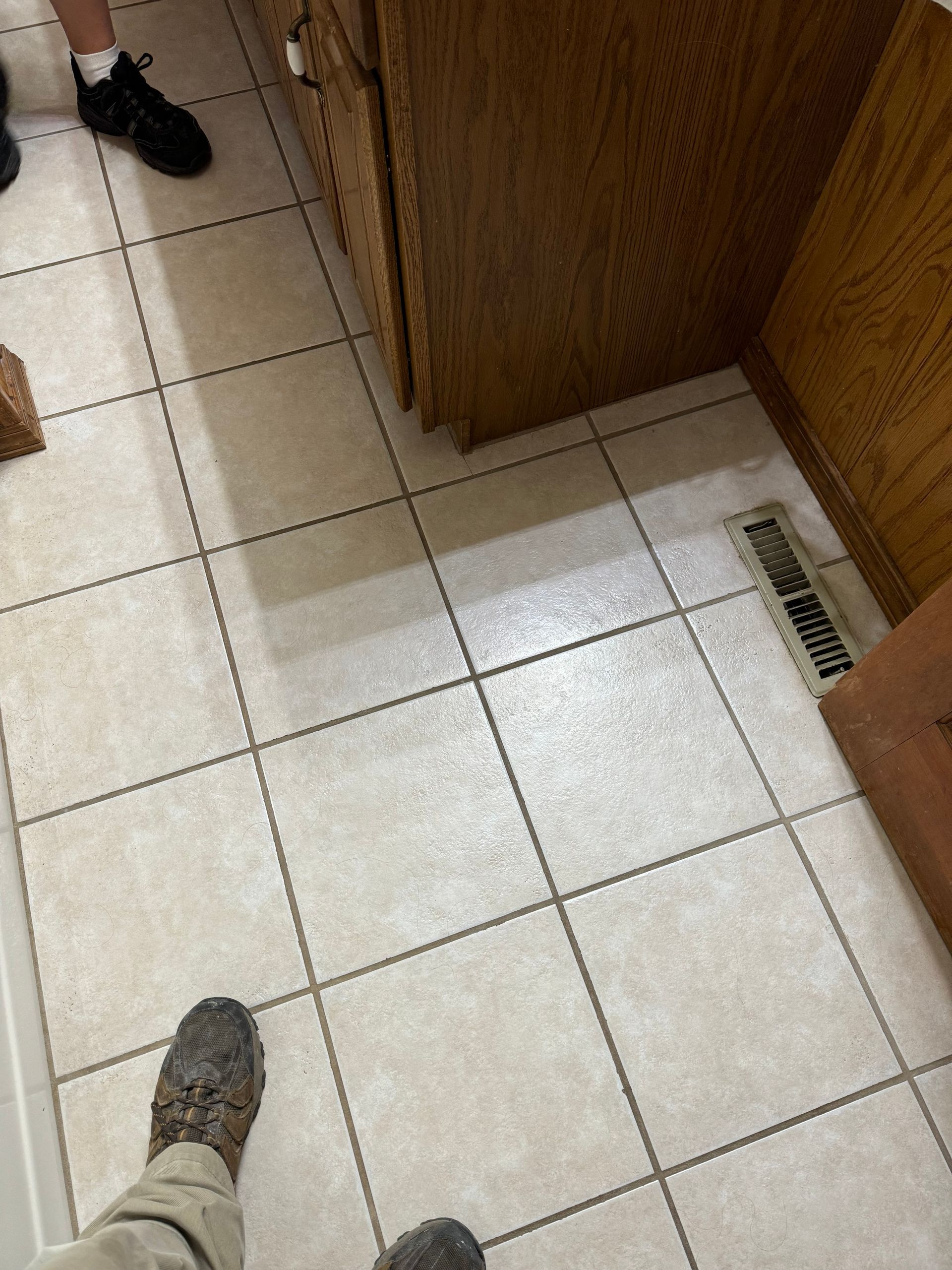 A person is standing on a tiled floor in a kitchen