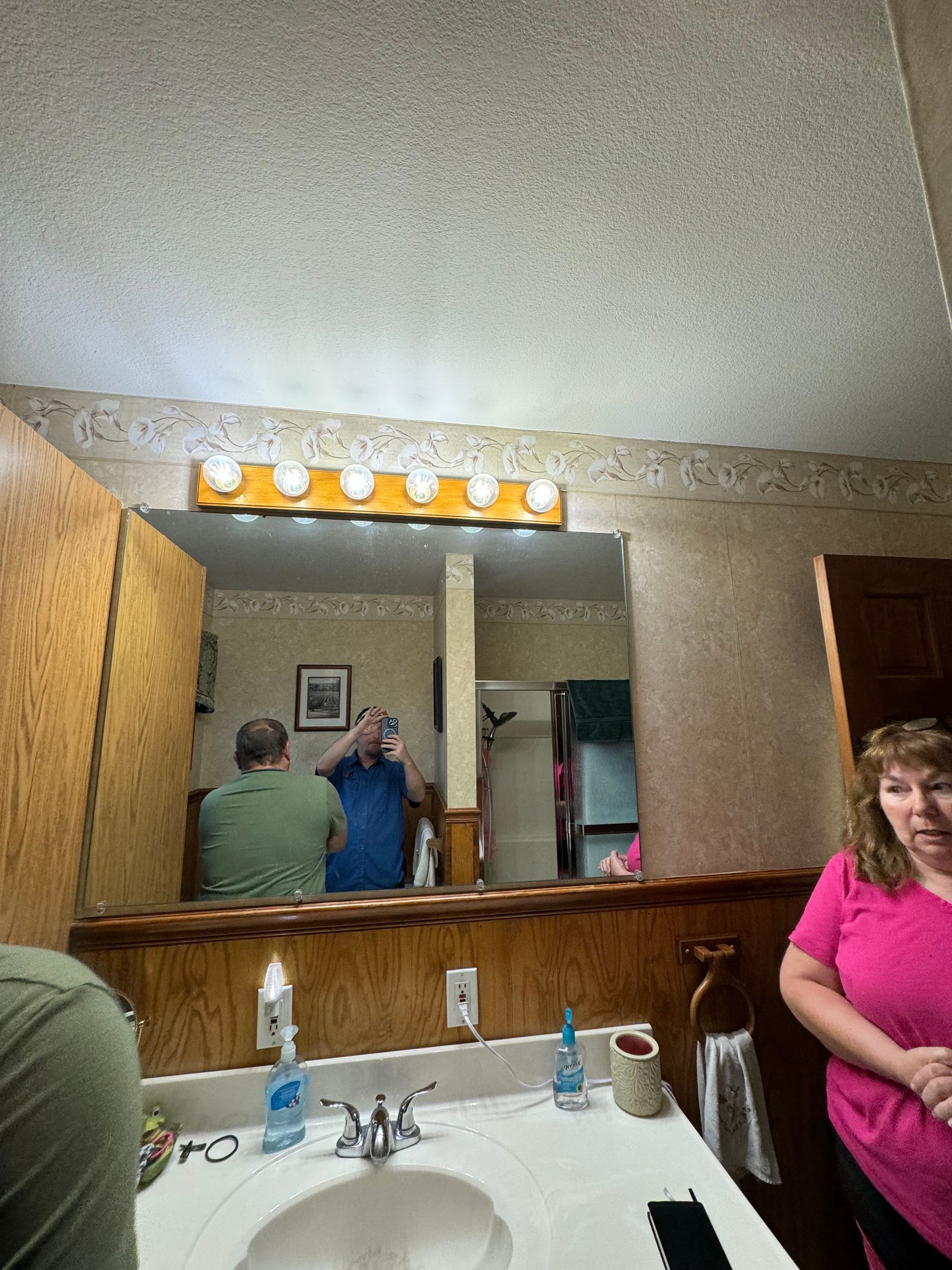 A man and a woman are standing in front of a bathroom mirror