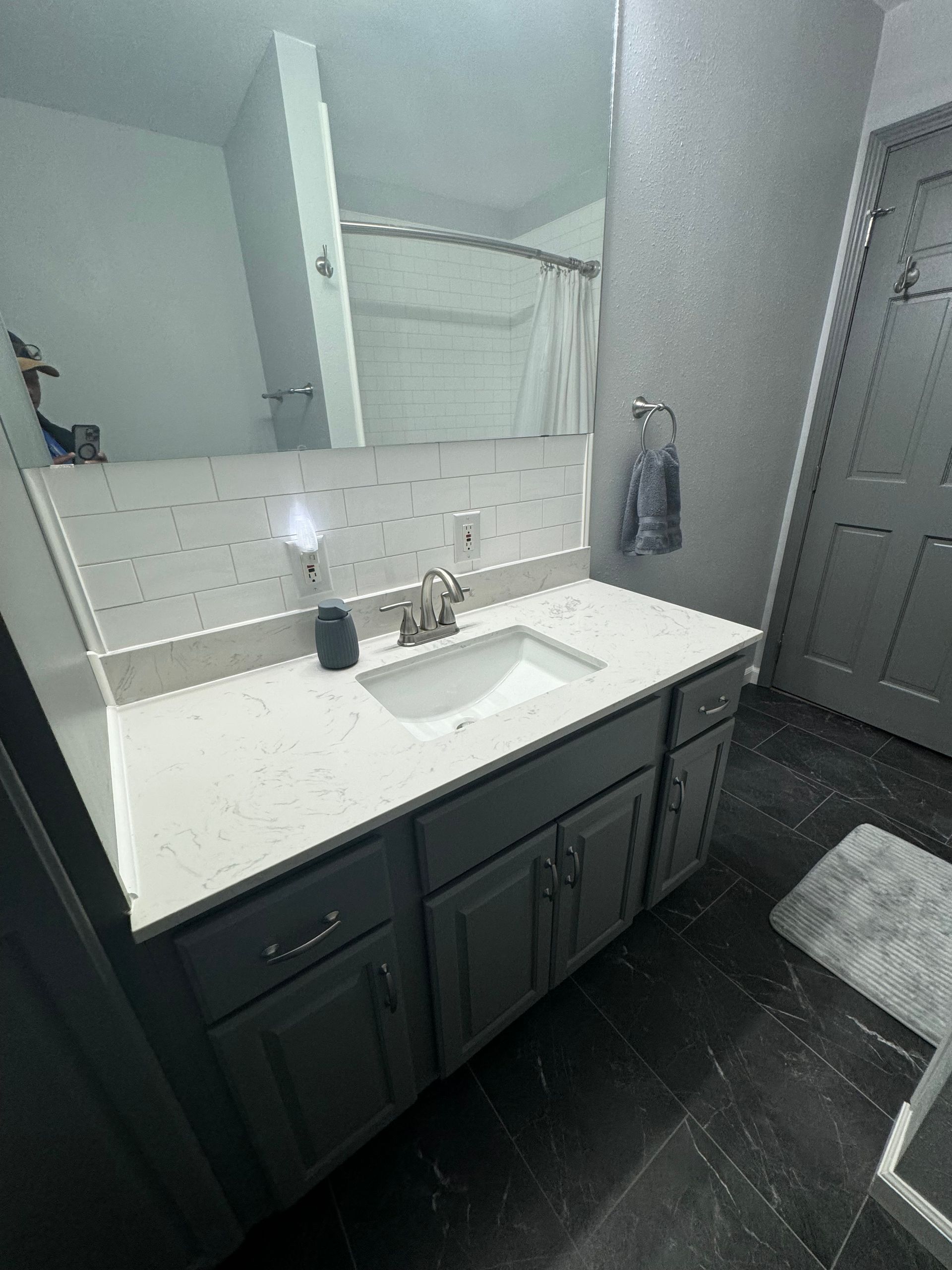 A bathroom with a sink, mirror, and cabinets