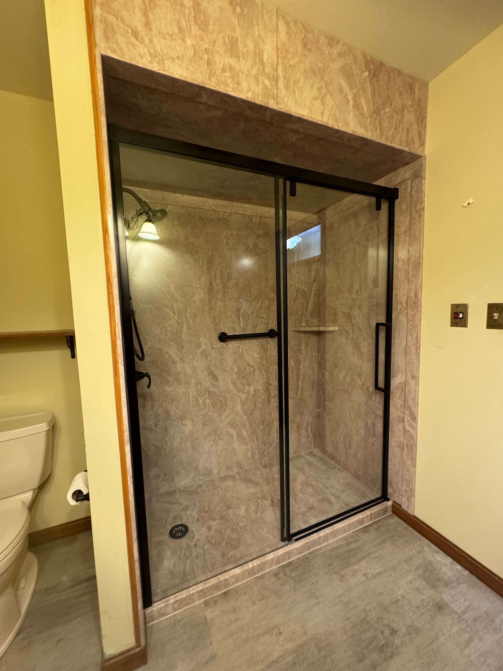 A bathroom with a toilet and a shower with sliding glass doors