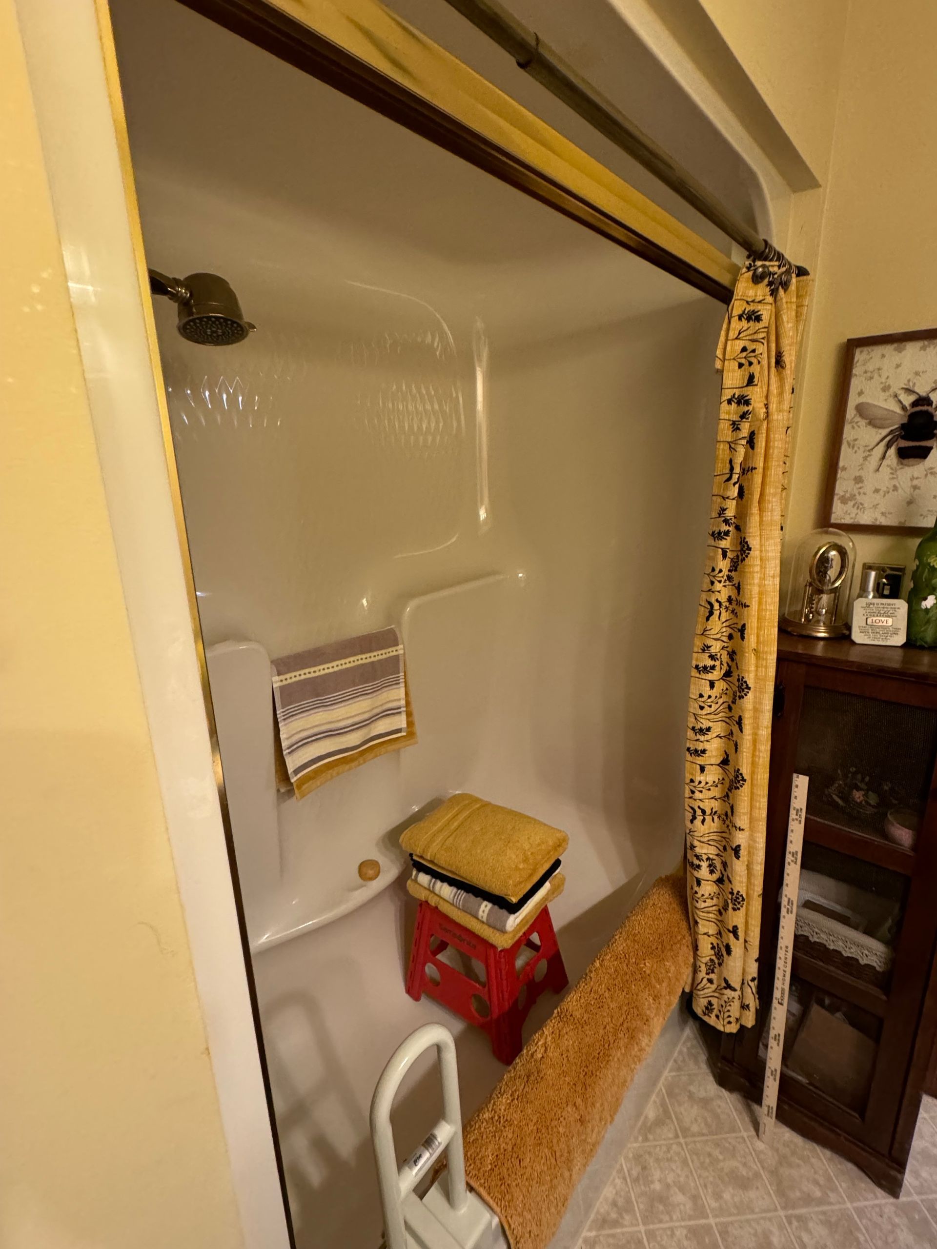 A bathroom with a shower stall and a stool