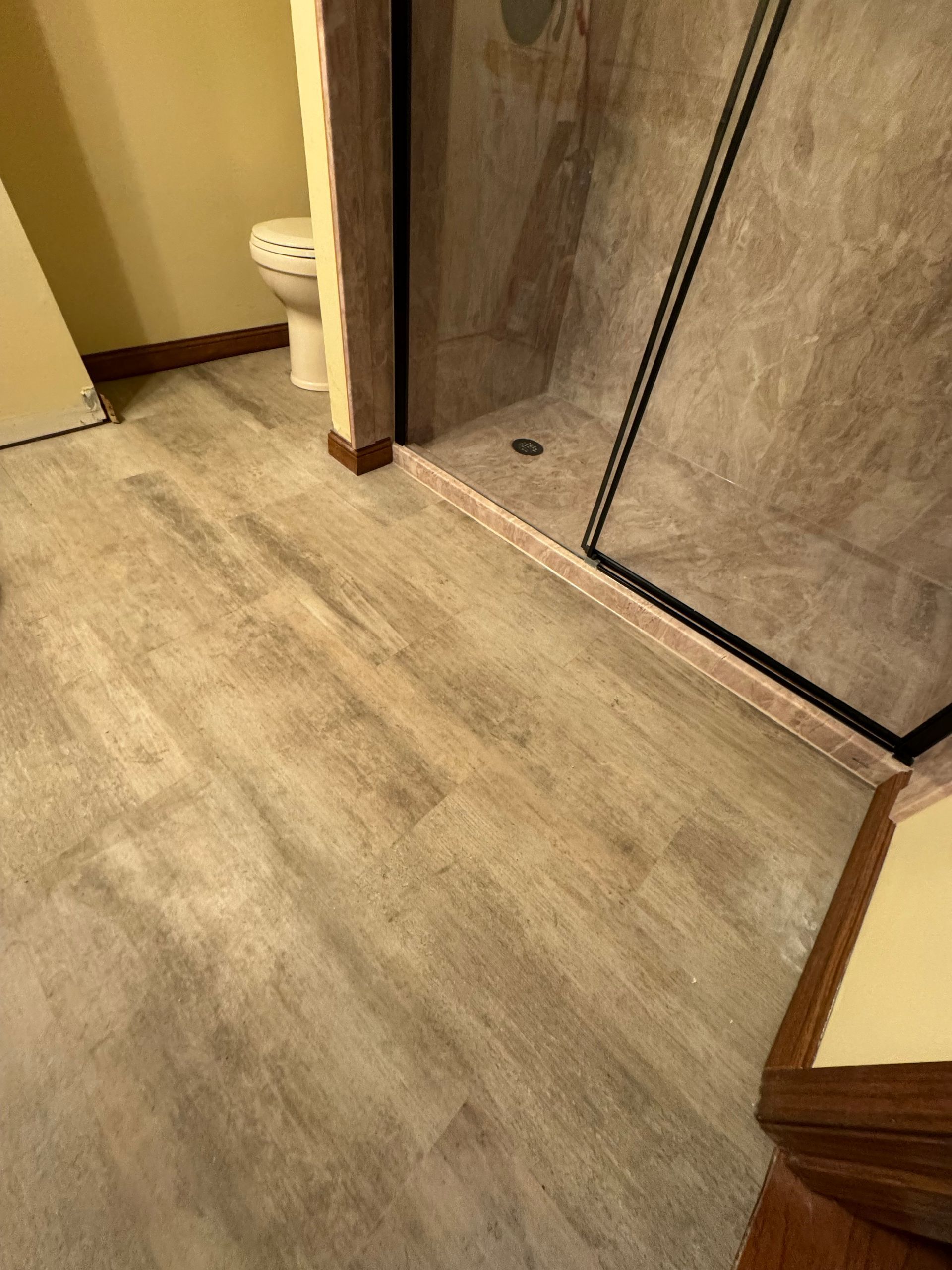 A bathroom with a toilet and a shower with sliding glass doors