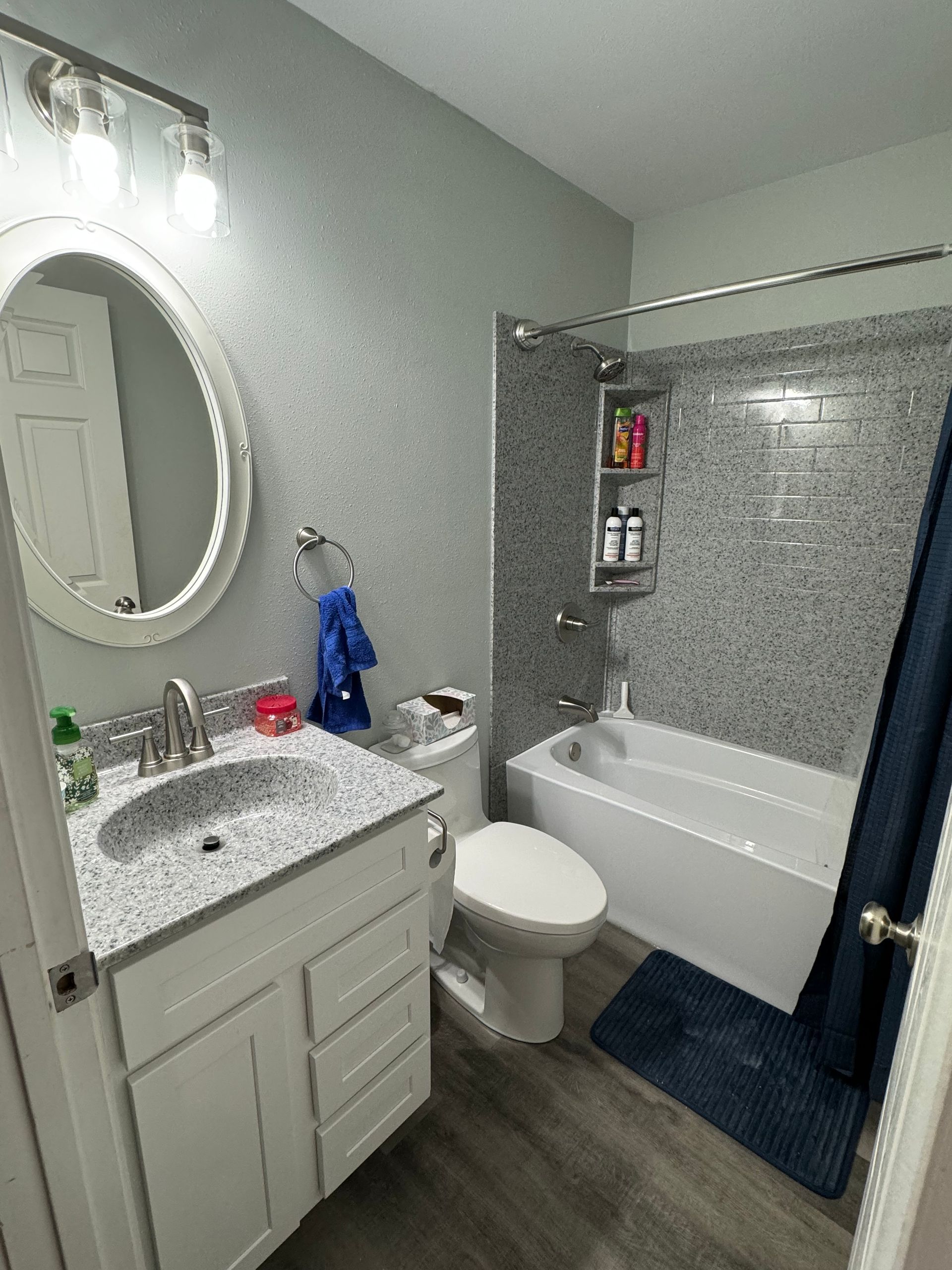 A bathroom with a sink, toilet, tub, and mirror