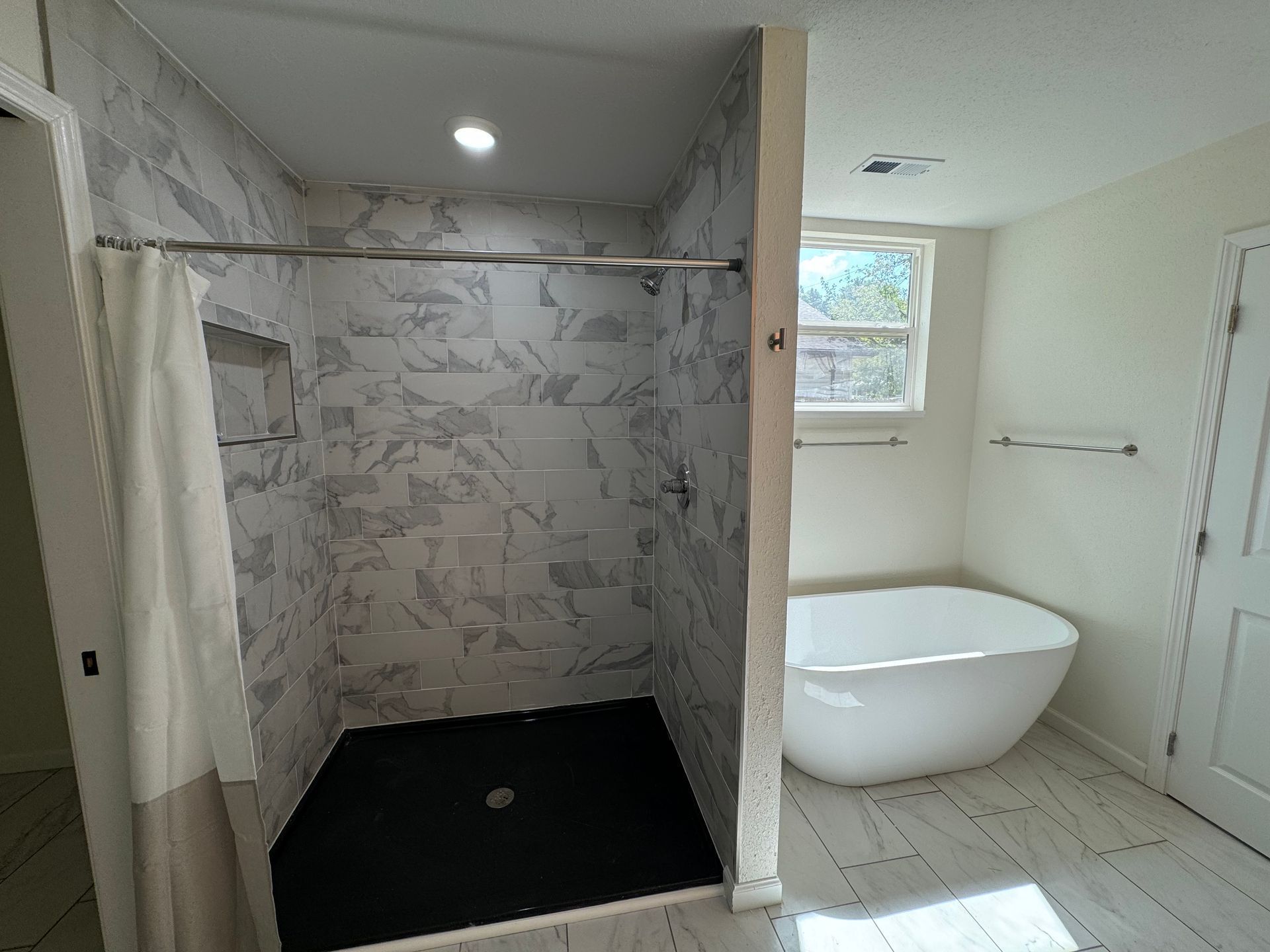 A bathroom with a tub, shower, and window