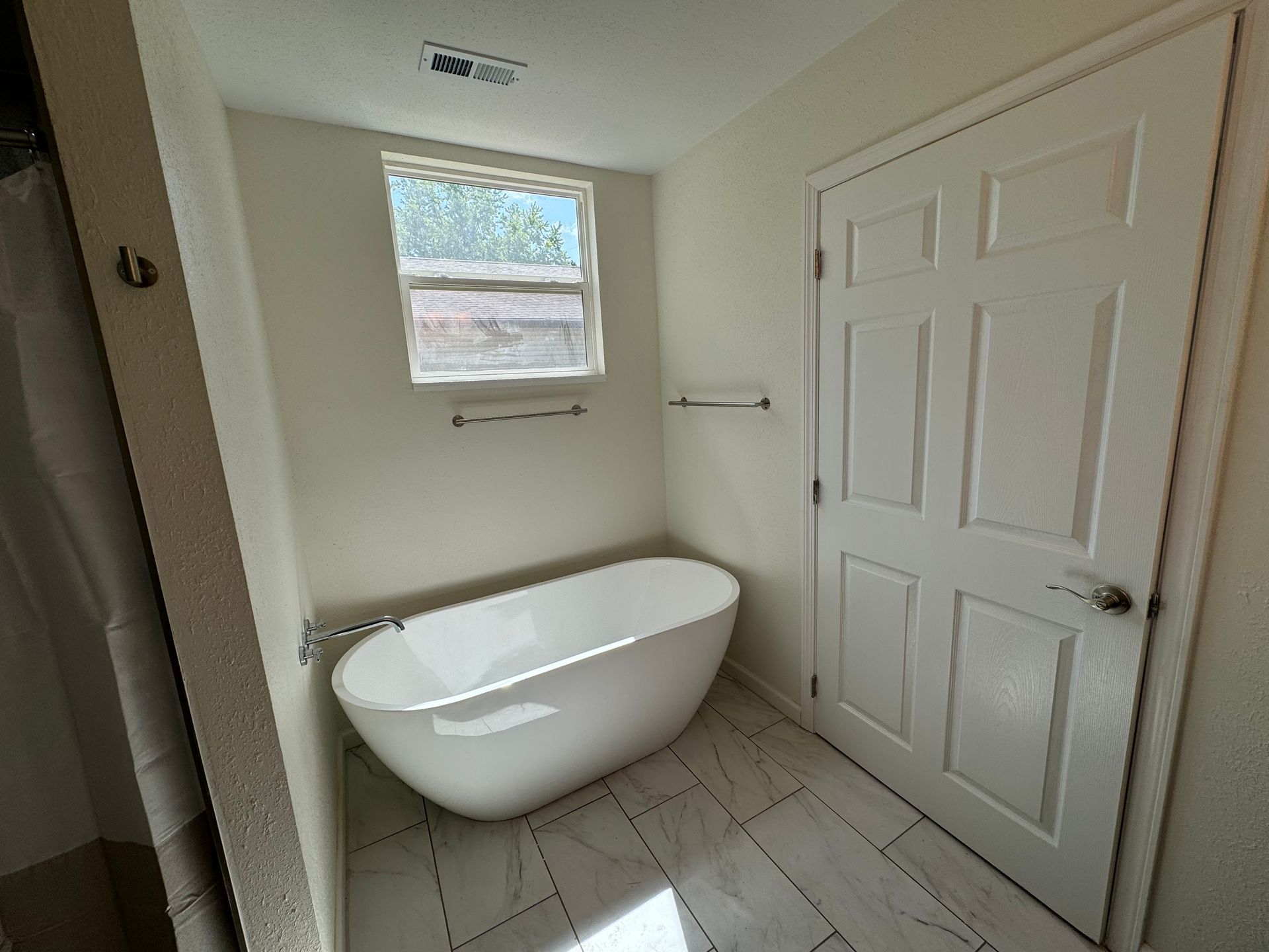 A bathroom with a bathtub and a window
