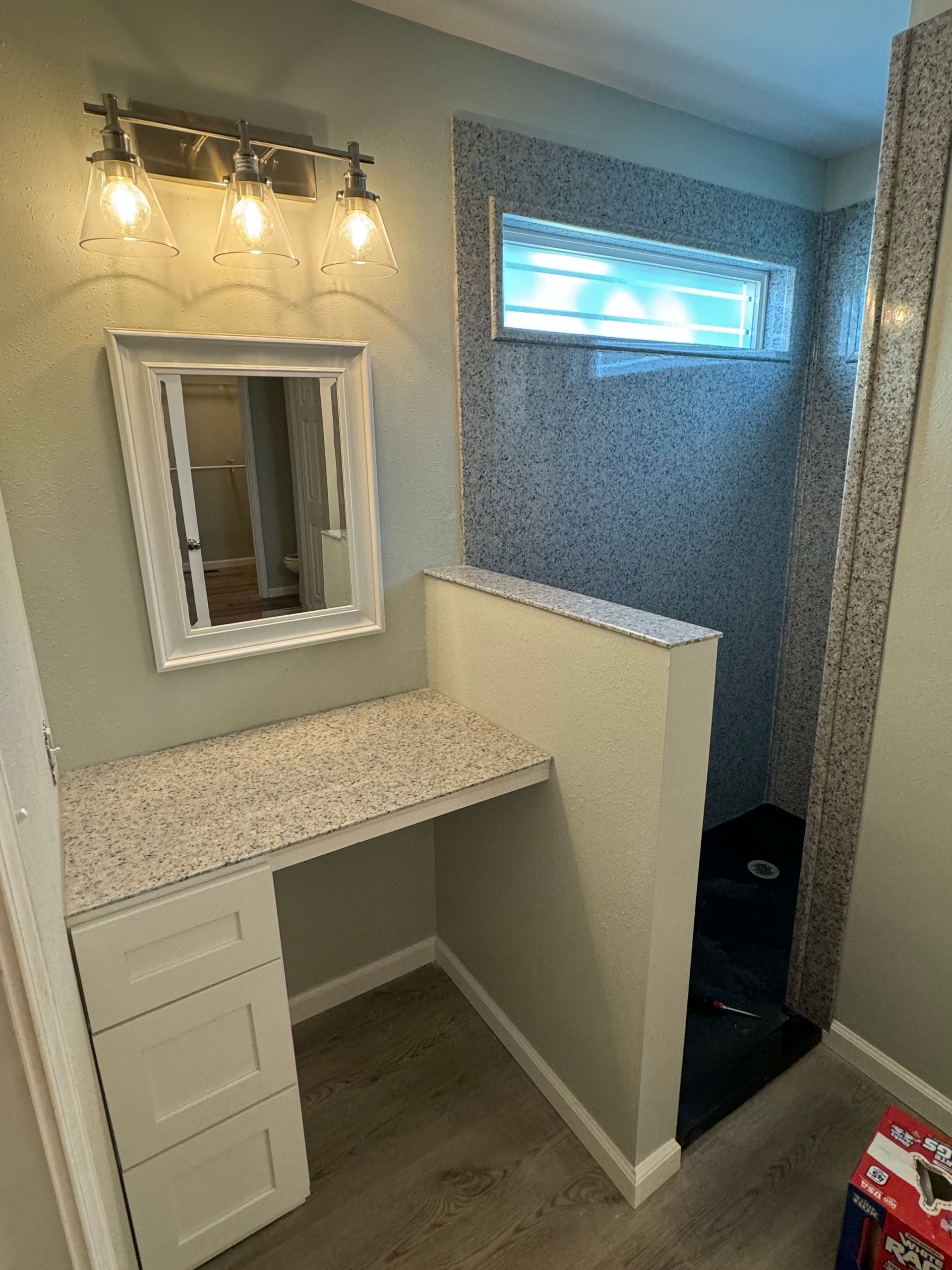 A bathroom with a vanity, mirror and shower