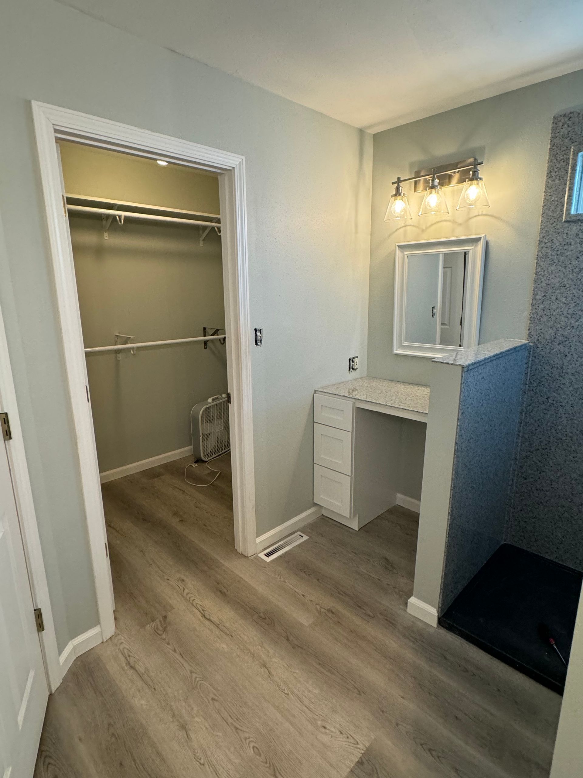 A bathroom with a walk-in closet and a vanity