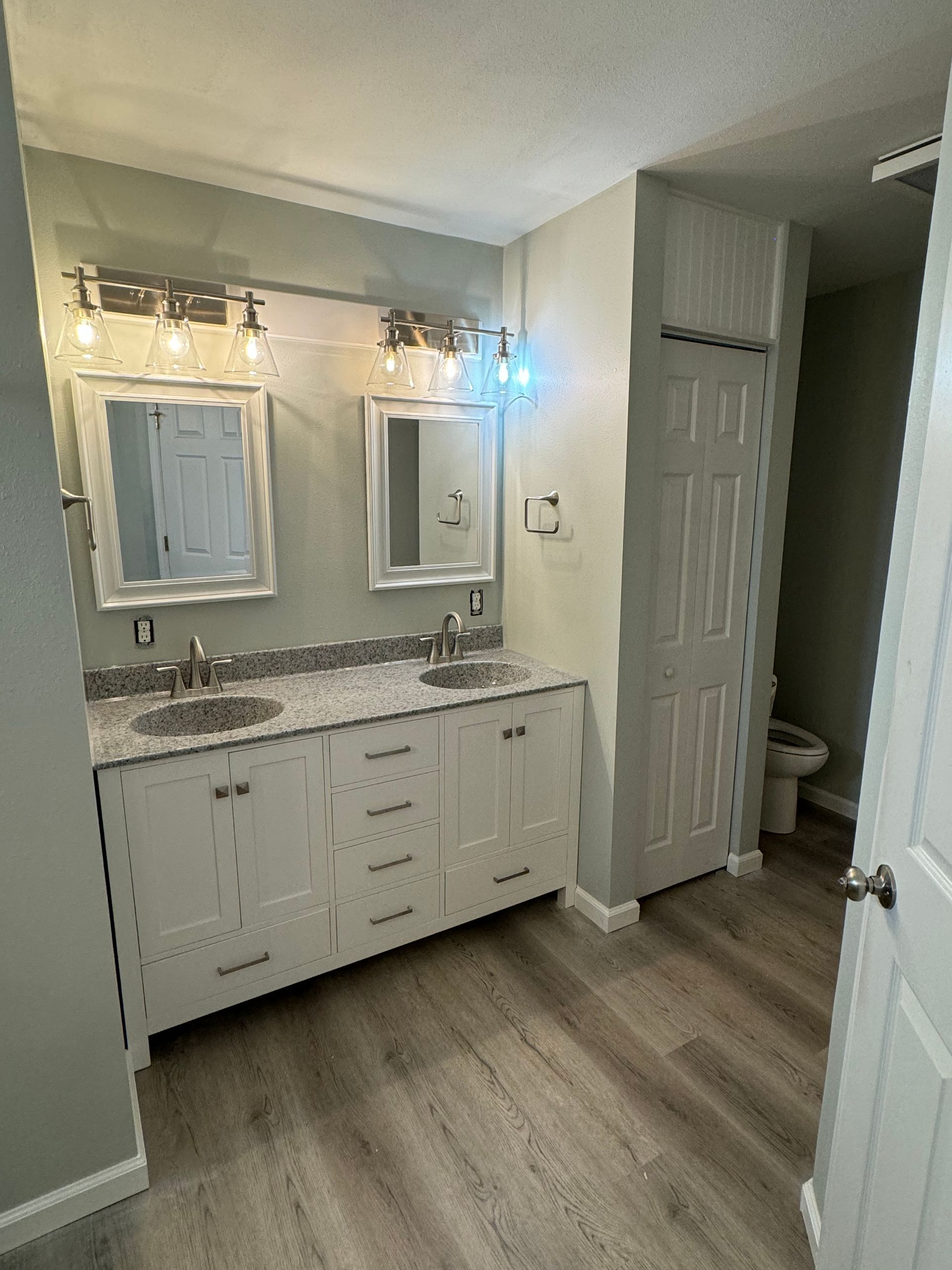 A bathroom with two sinks, two mirrors, and a toilet