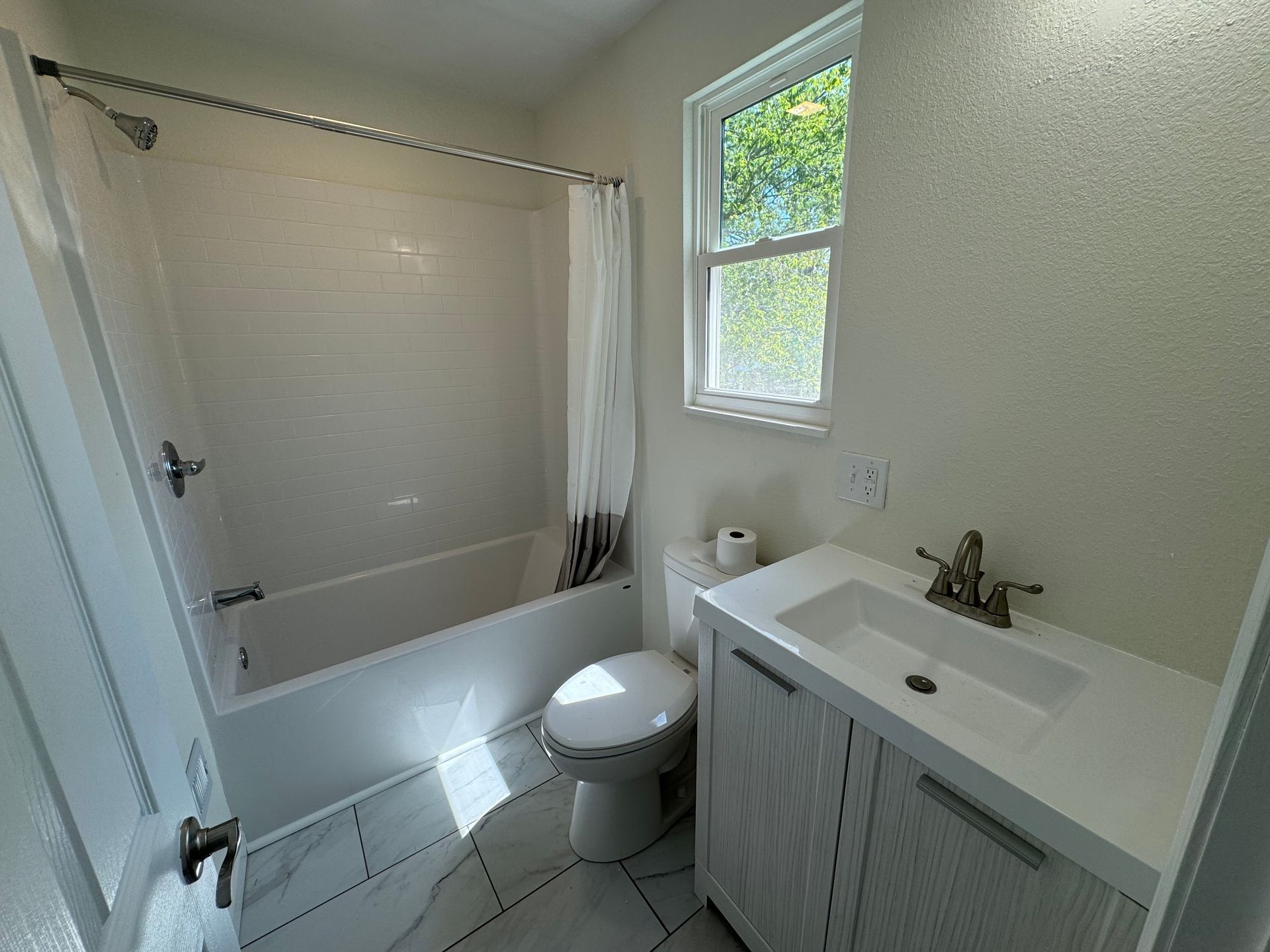 A bathroom with a toilet, sink, bathtub and window