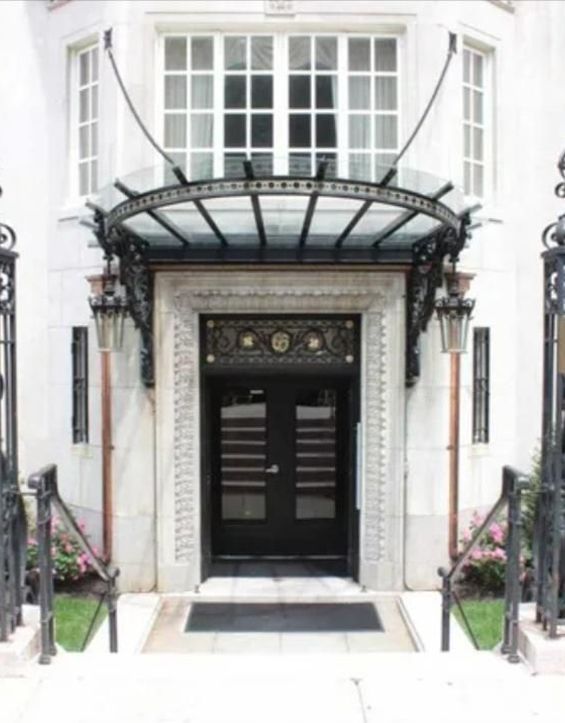 A white building with a black door and a glass canopy